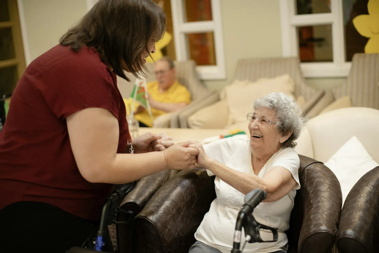A caregiver holding hands and laughing with a resident